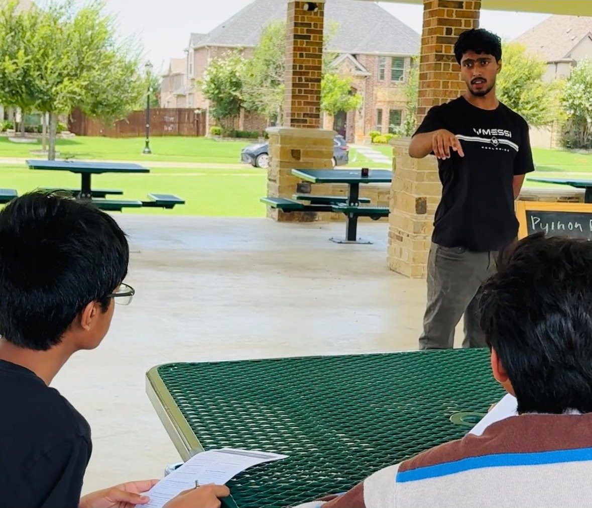 Deeptanshu presenting at an outdoor picnic table while others sit in the foreground